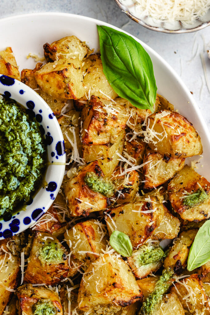 Closeup of these Pesto roasted potatoes topped with parmesan cheese and fresh basil.