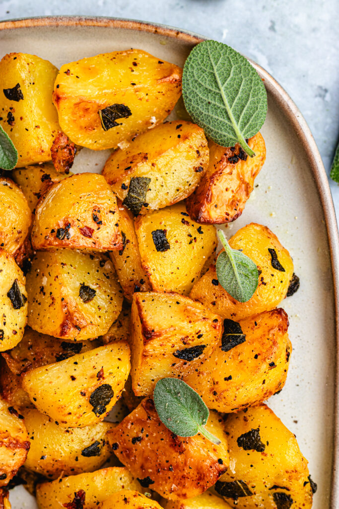 Roasted potatoes with sage on a serving platter. 