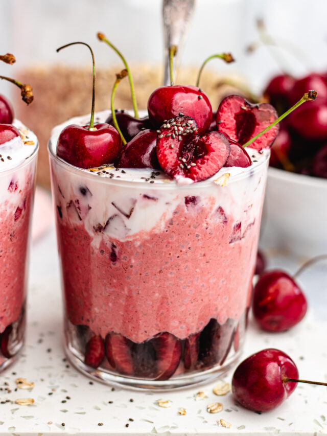 Cherry overnight oats in 2 classes topped with yoghurt and fresh cherries.