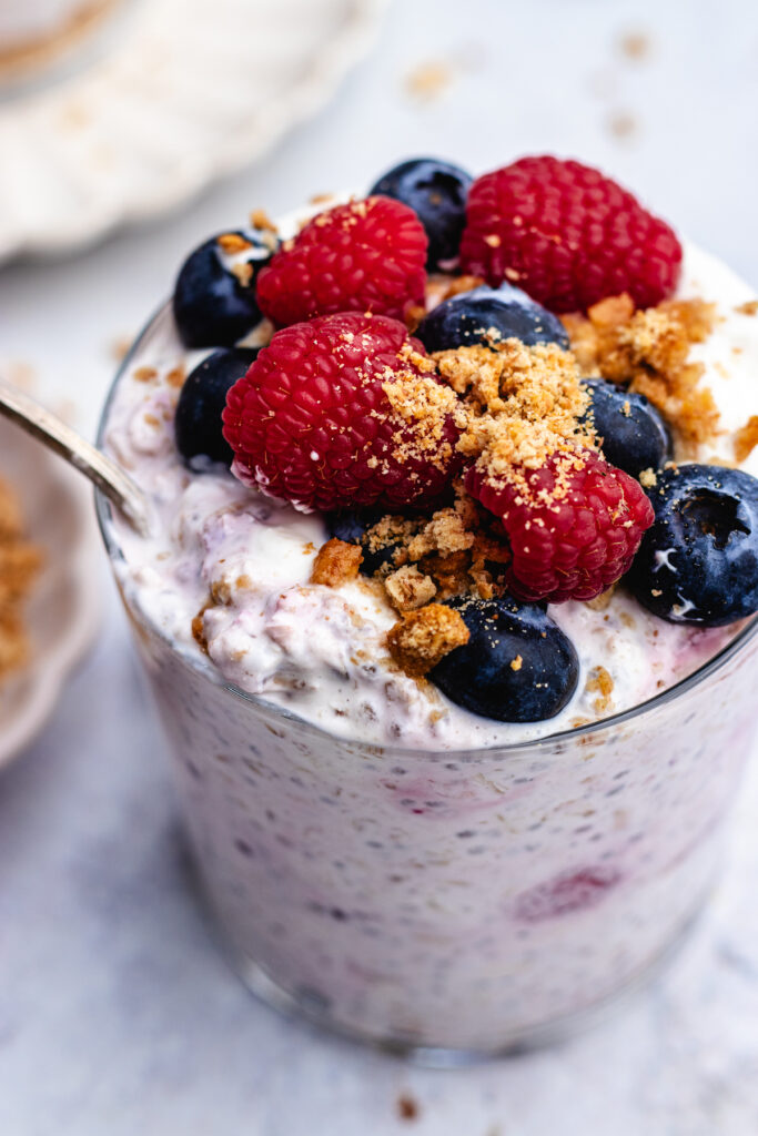 Overnight oats in two glasses with cookie crumbs and fresh berries.
