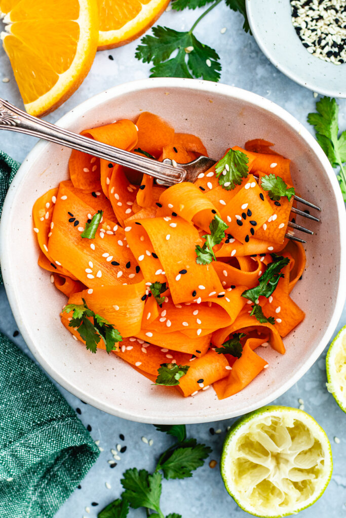 The carrot salad in a bowl topped with sesame seeds and cilantro.