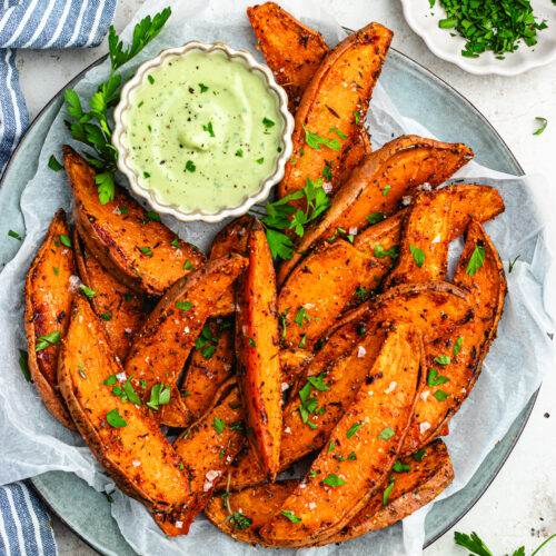 The wedges on a plate topped with parsley and a bowl of sauce.