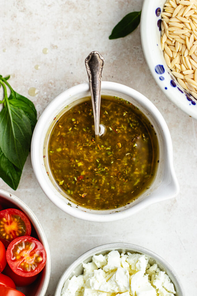 The dressing in a small bowl with a spoon. 