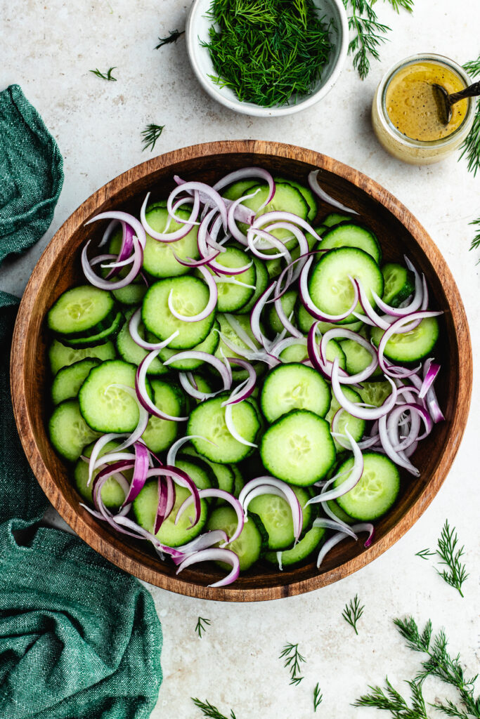 The cucumber sliced and red onion in a salad bowl.