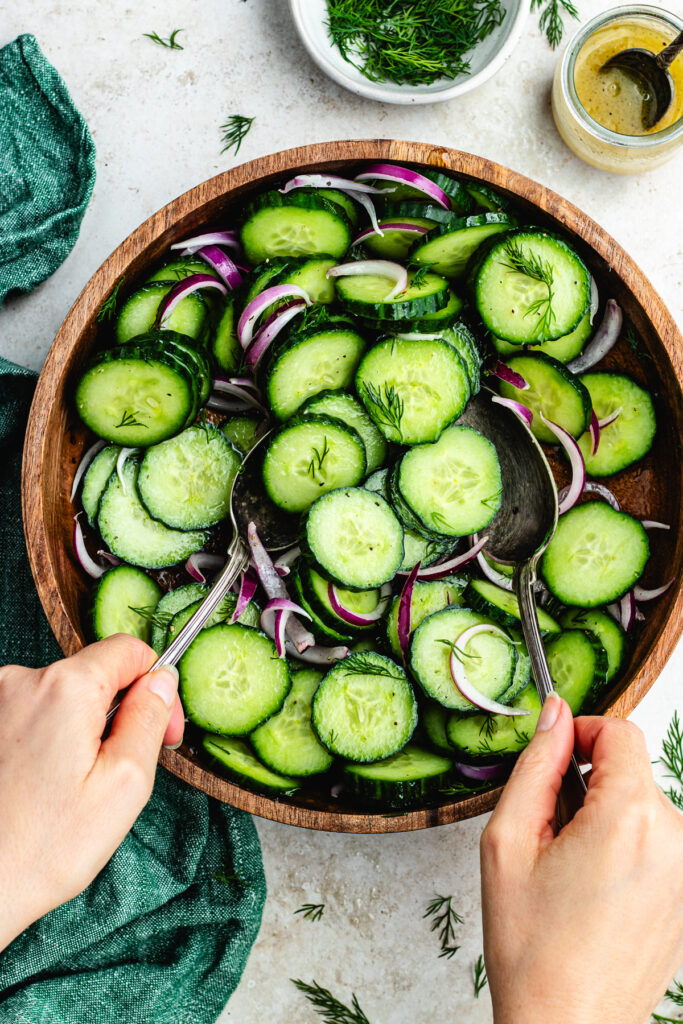 Tossing the salad together with 2 spoons.