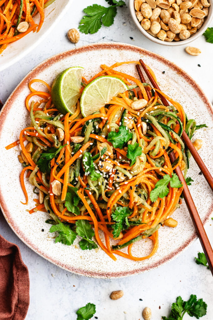 The salad on a small plate with wooden chopsticks.