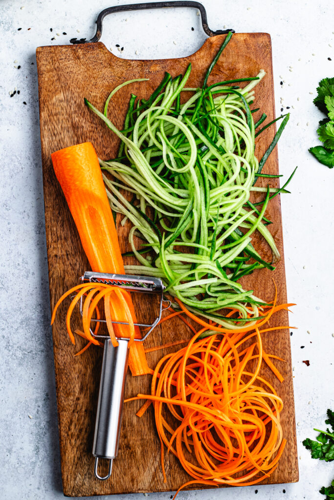 The shredded carrots and cucumber on a cutting board. 