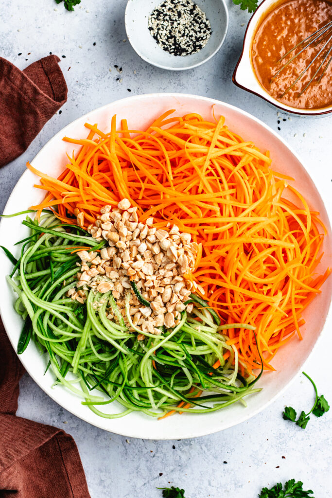 The vegetables and chopped peanuts in a salad bowl.