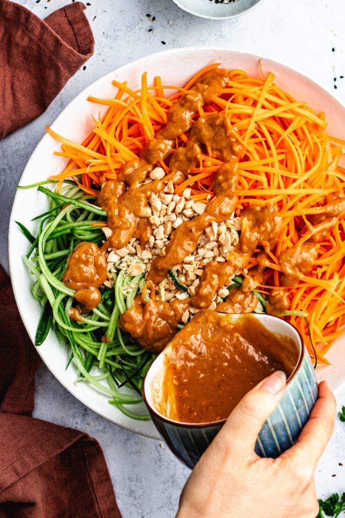 Pouring over the dressing over the vegetables in the salad bowl.