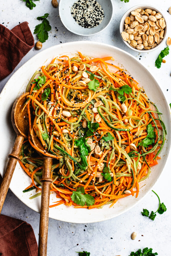 The salad in a salad bowl topped with chopped peanuts and coriander. 