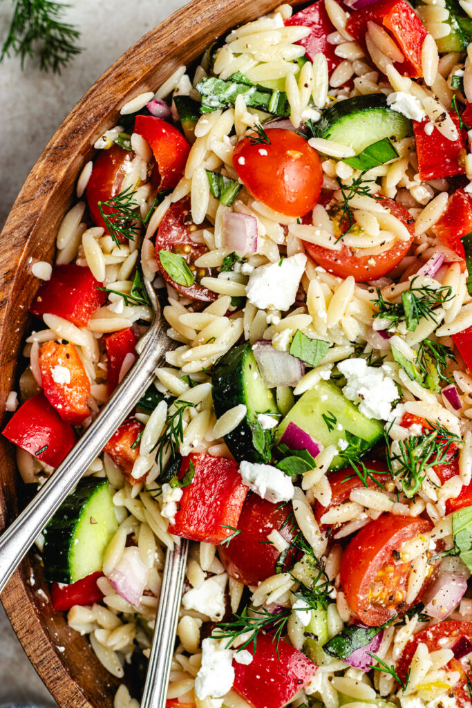 The salad in a wooden salad bowl topped with lemon slices.