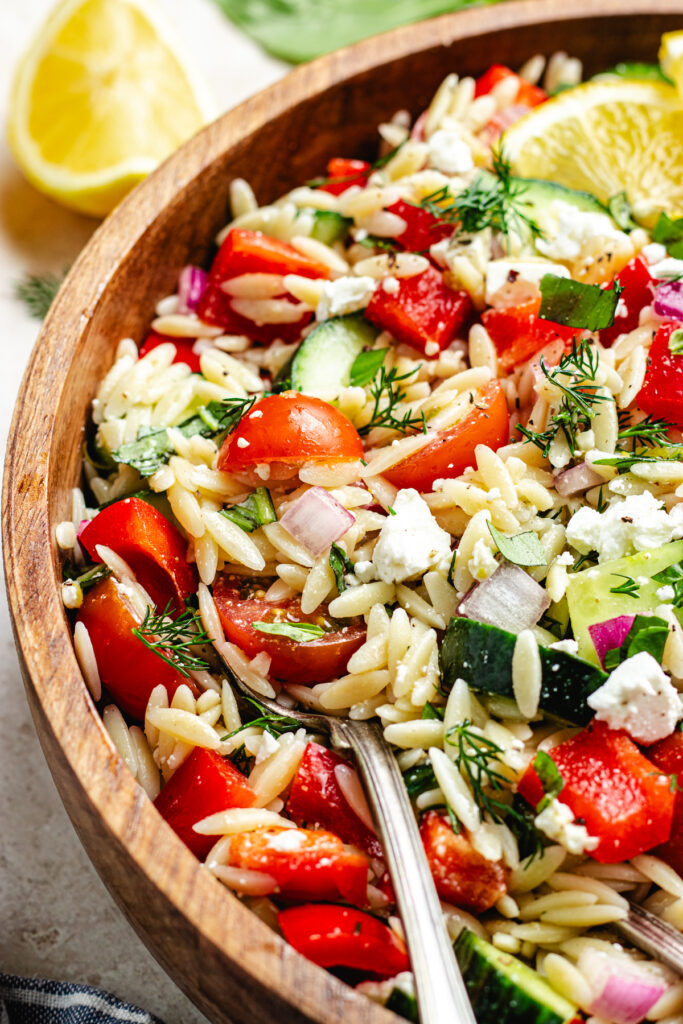 The salad in a wooden salad bowl topped with lemon slices.