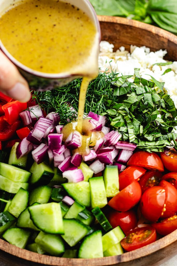 Pouring over the dressing onto the salad.