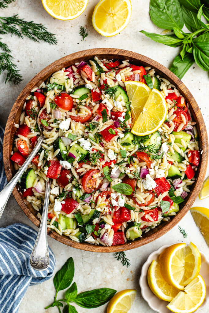 The salad in a wooden salad bowl topped with lemon slices.