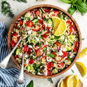 The salad in a wooden salad bowl topped with lemon slices.