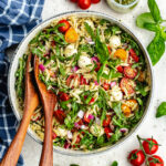 The salad in a salad bowl topped with fresh basil.