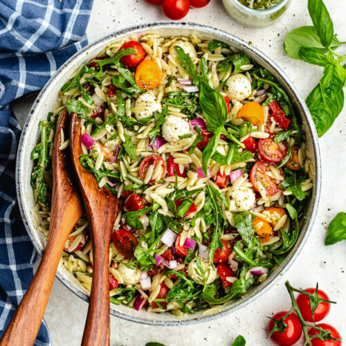 The salad in a salad bowl topped with fresh basil.