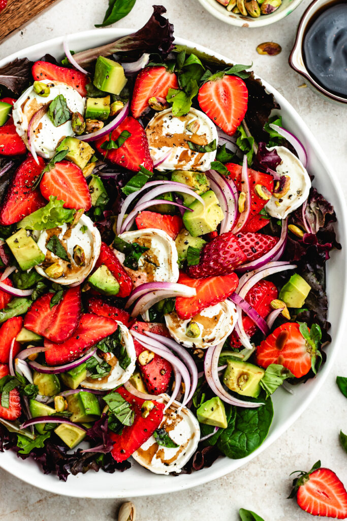 The salad in a big salad bowl topped with pistachios.