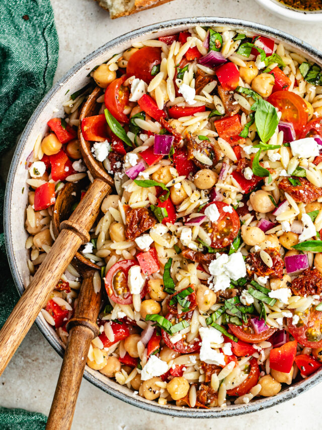 The salad in a big bowl with a small bowl of dressing and bread on the side.