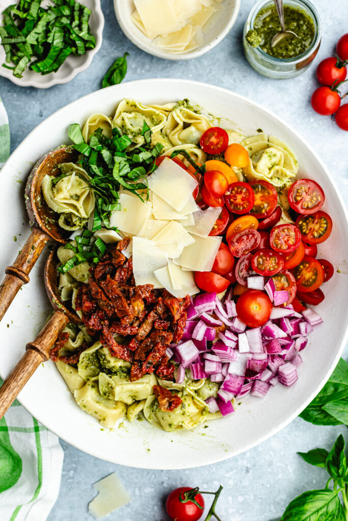 The added vegetables and cheese to the bowl with the pasta. 