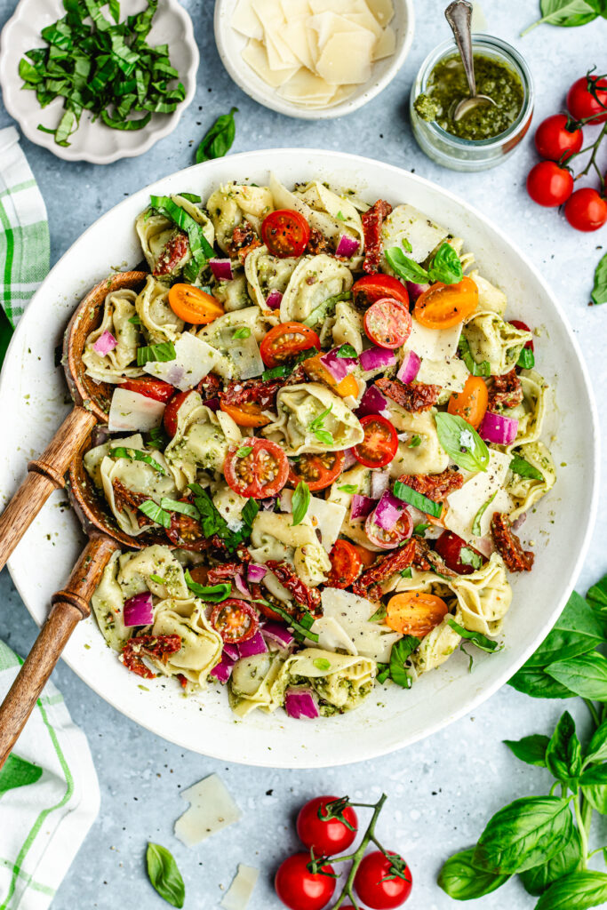 The tortellini salad in a serving bowl topped with fresh basil.