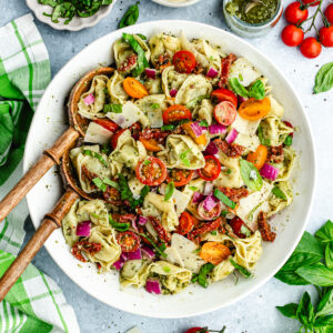 The tortellini salad in a serving bowl topped with fresh basil.