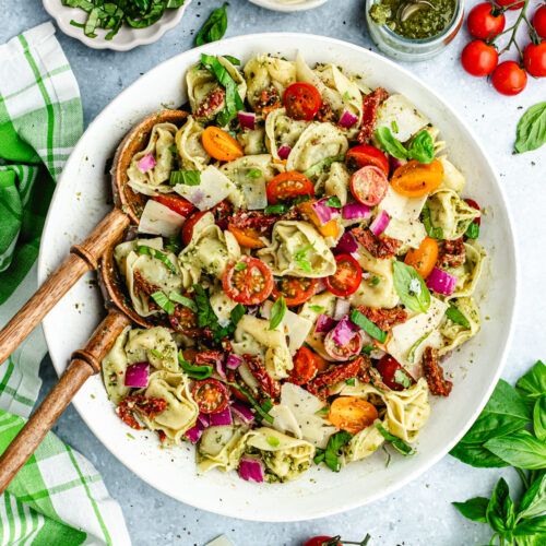 The tortellini salad in a serving bowl topped with fresh basil.