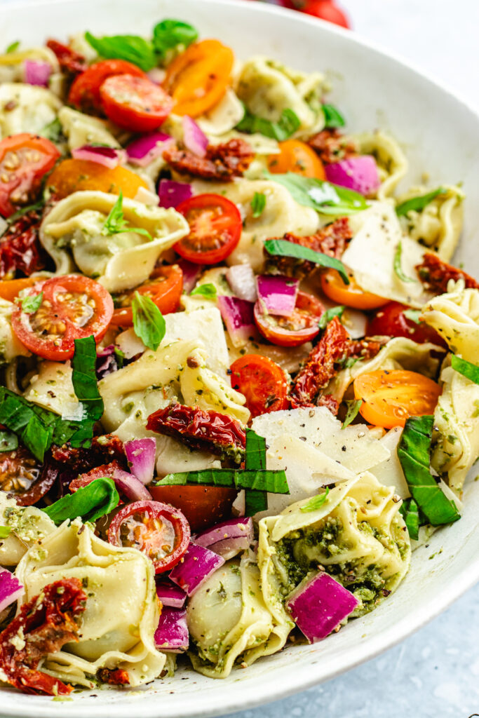 The tortellini salad in a serving bowl topped with fresh basil.