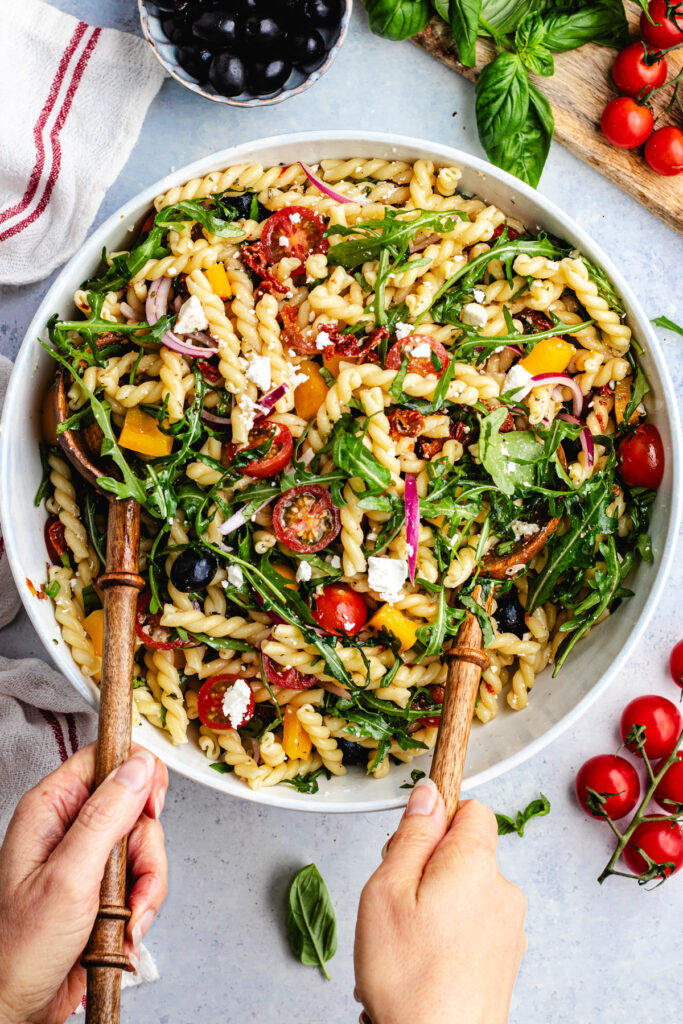 Tossing together the salad with salad spoons. 