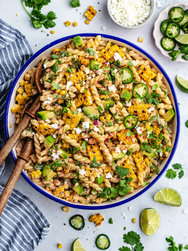The pasta salad in a salad bowl topped with jalapeño slices.