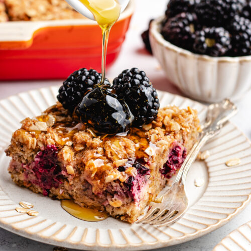 Pouring maple syrup over a pice of overnight oats topped with blackberries.