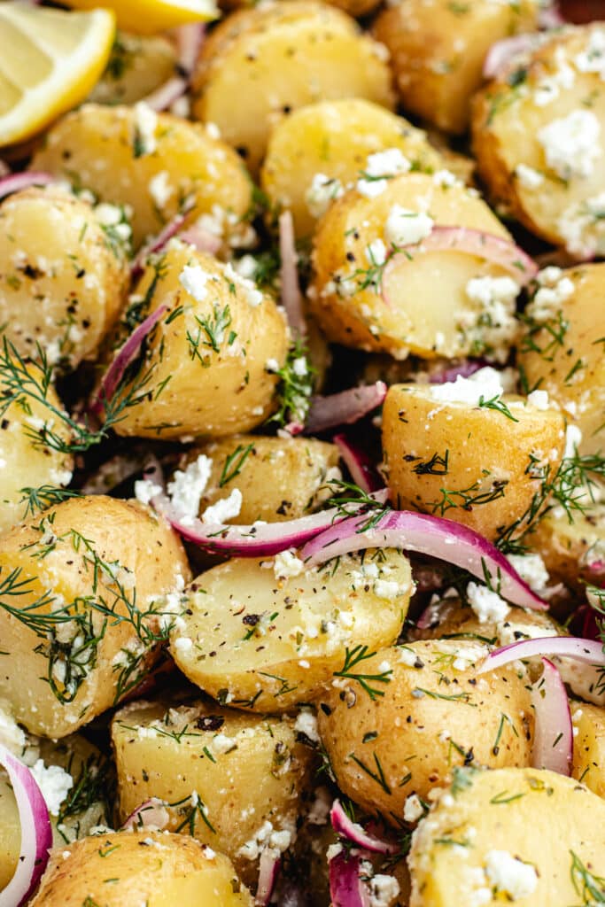 The potato salad in a bowl topped with dill and lemon.