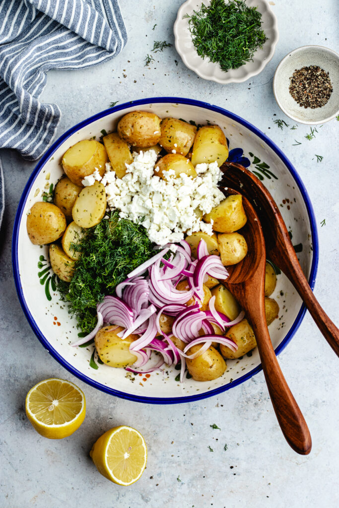 Adding the dill, feta cheese and onion to the potatoes.