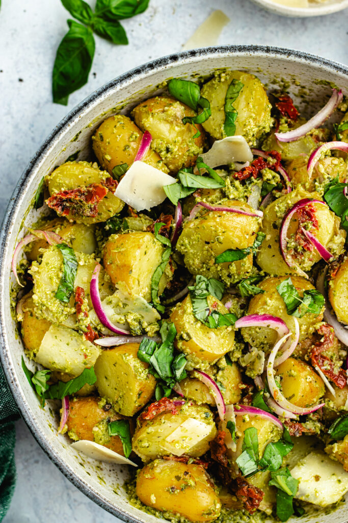 The potato salad in a bowl topped with fresh basil and parmesan cheese.