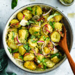 The potato salad in a bowl topped with fresh basil and parmesan cheese.
