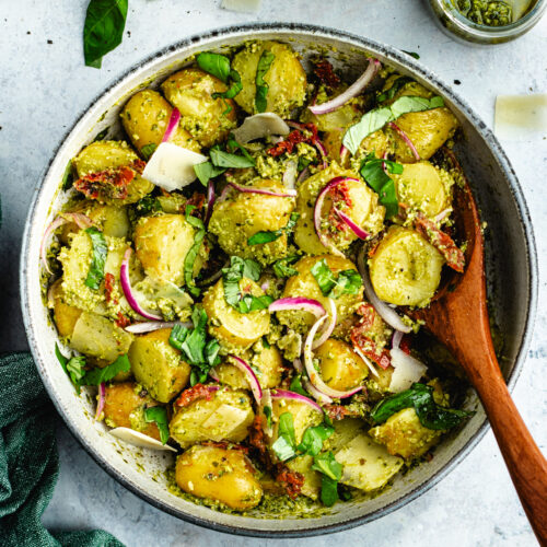 The potato salad in a bowl topped with fresh basil and parmesan cheese.