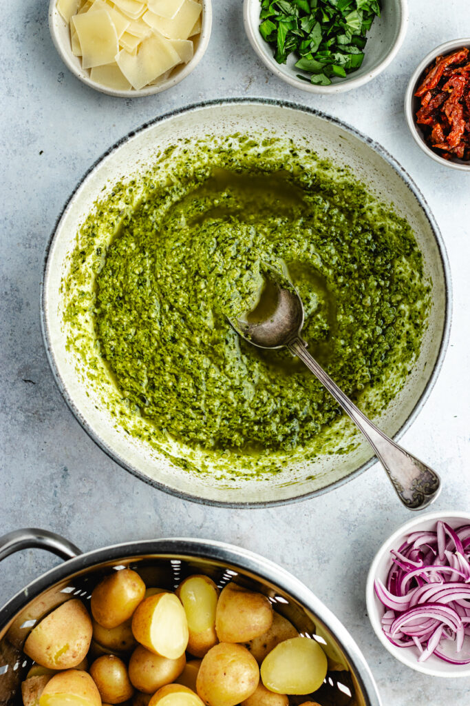 The pesto sauce in a bowl with a spoon.