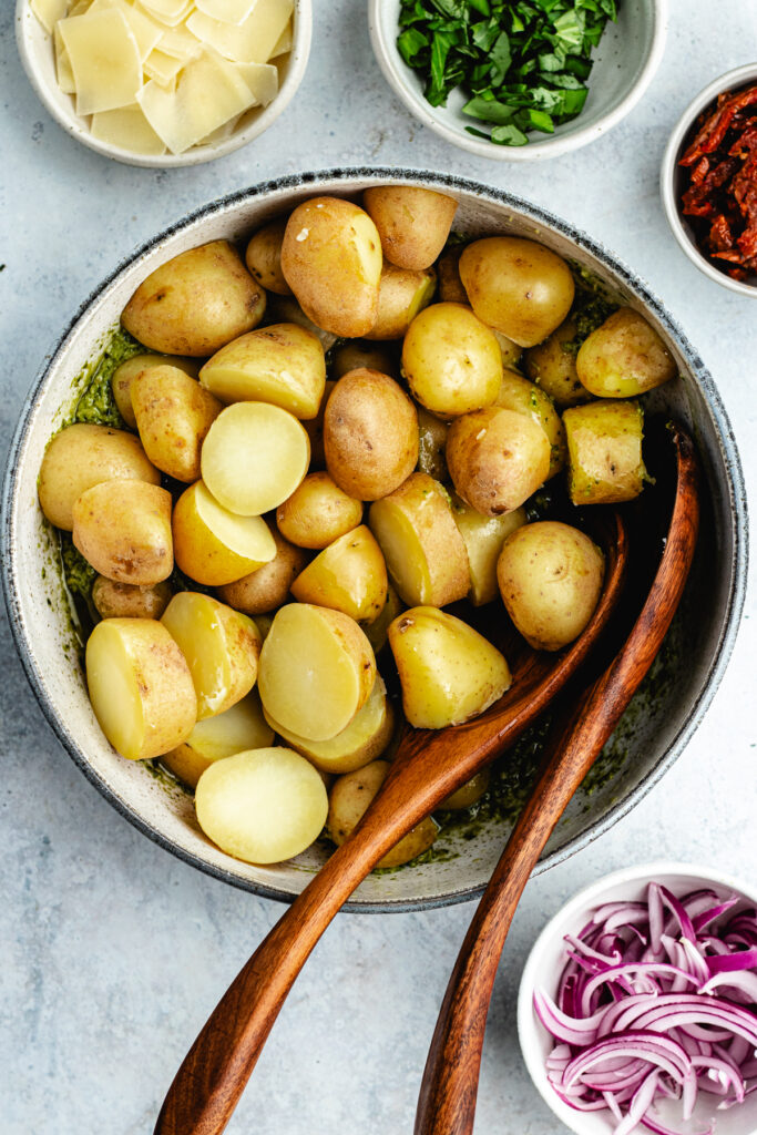 The potatoes added to the bowl with the pesto.