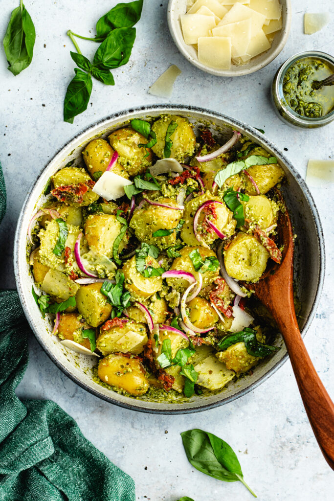 The potato salad in a bowl topped with fresh basil and parmesan cheese.
