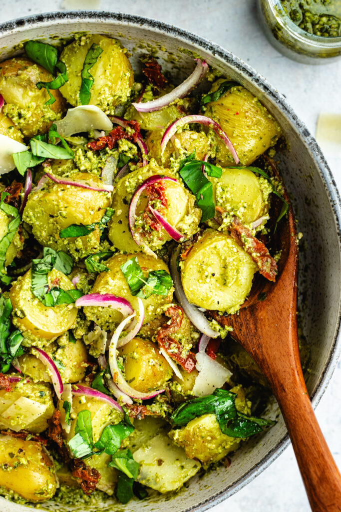 The potato salad in a bowl topped with fresh basil and parmesan cheese.