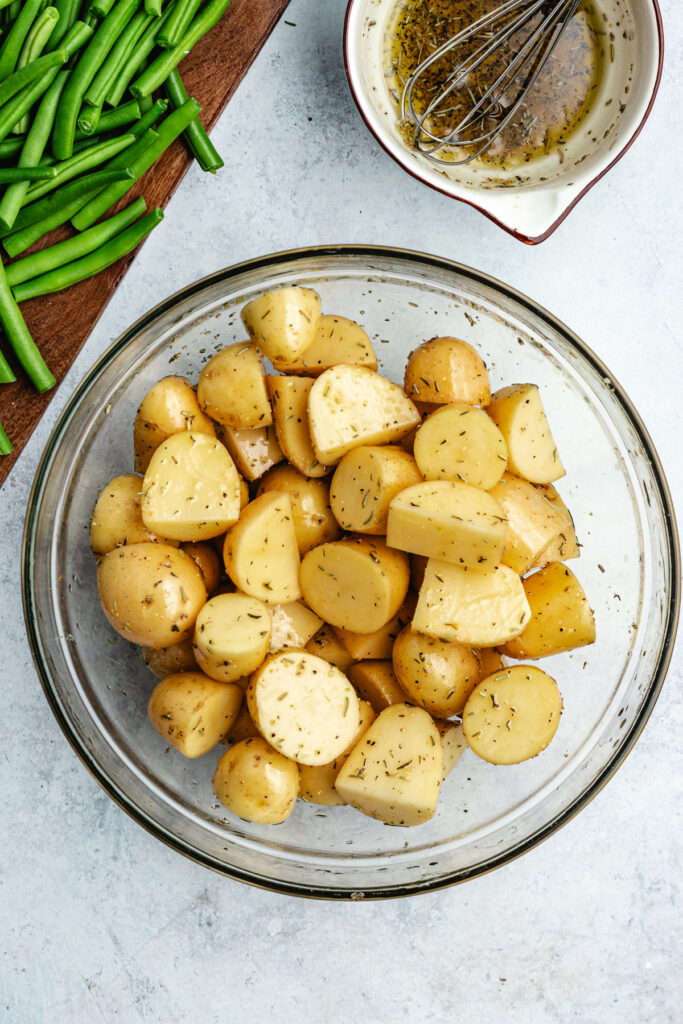 The potatoes in a bowl with the oil and spices.