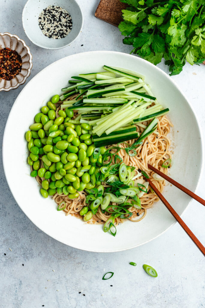 The added vegetables to the bowl with the noodles.