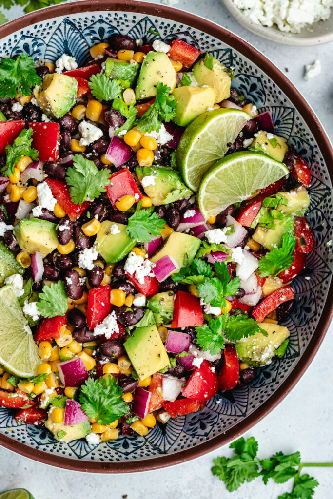 The salad in a serving bowl topped with fresh cilantro and slices of lime.