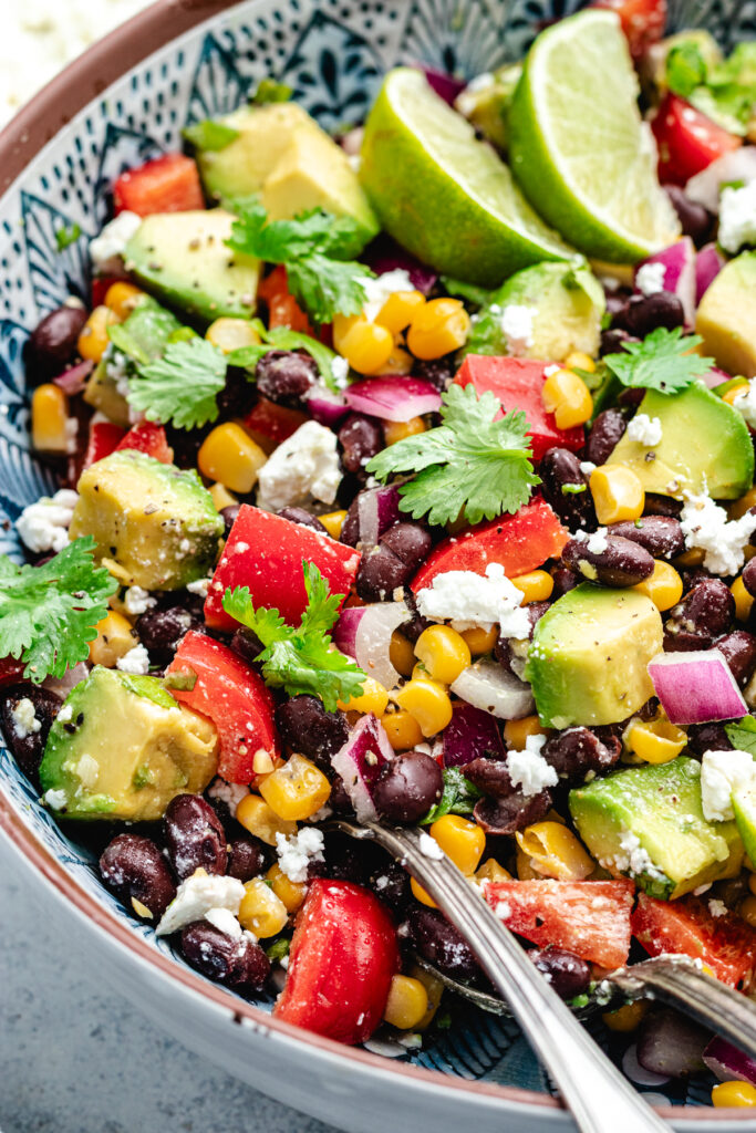 The salad in a serving bowl topped with fresh cilantro and slices of lime.