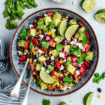 The salad in a serving bowl topped with fresh cilantro and slices of lime.