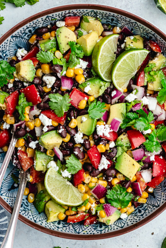 The salad in a serving bowl topped with fresh cilantro and slices of lime.