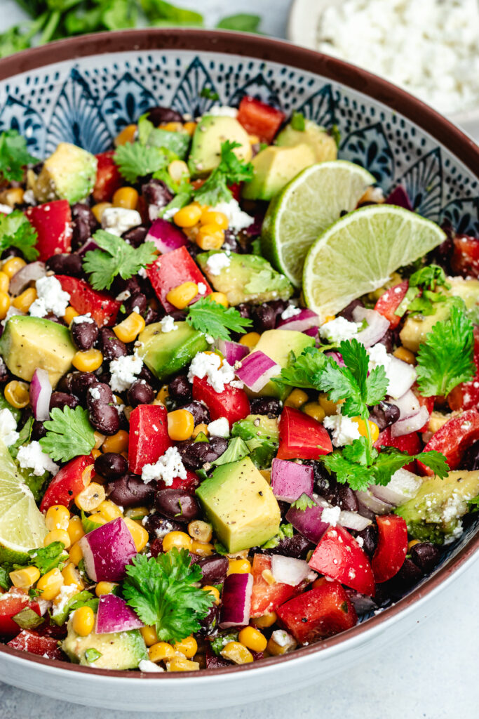 The salad in a serving bowl topped with fresh cilantro and slices of lime.