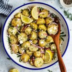 The potato salad in a bowl with a wooden spoon.