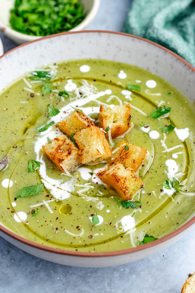 The soup in a bowl topped with croutons, cream and parmesan cheese.
