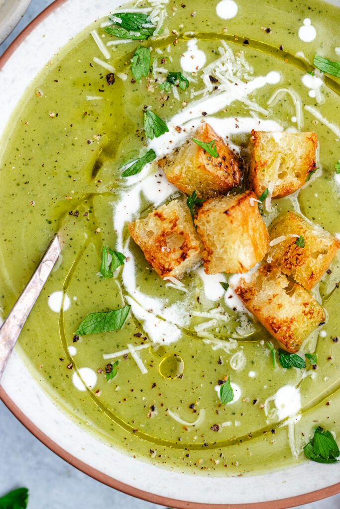 The soup in a bowl topped with croutons, cream and parmesan cheese.